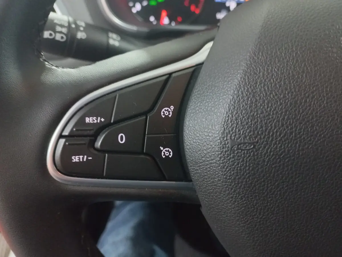 Gros plan sur les commandes du régulateur de vitesse au volant noir de la Renault Mégane Business 2022.