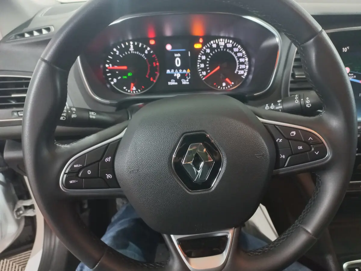 Vue rapprochée du volant noir de la Renault Mégane Business avec tableau de bord numérique allumé.