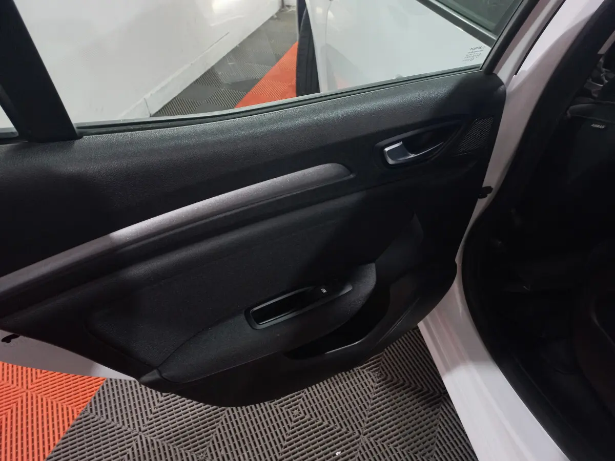 Intérieur côté gauche de la porte arrière d'une Renault Mégane Business Blue dCi blanche, avec poignée et commande de vitre.