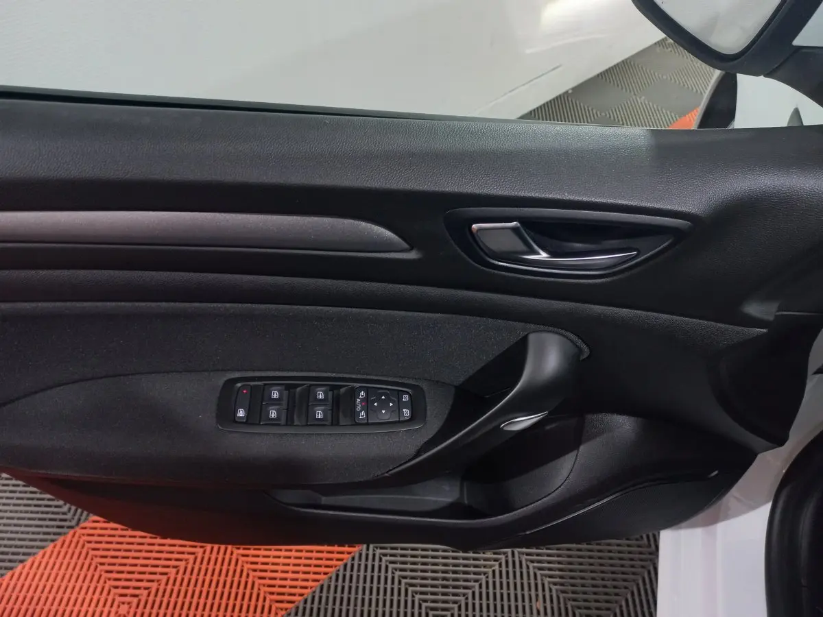 Vue rapprochée de la porte côté gauche d'une Renault Mégane Business blanche, avec commandes électriques des vitres.