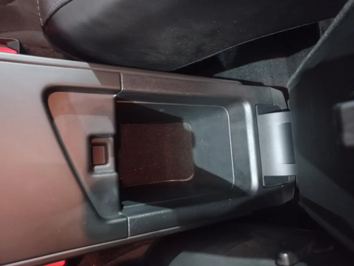 Vue rapprochée du rangement central noir ouvert entre les sièges avant d'une Renault Mégane Business blanche 2022.