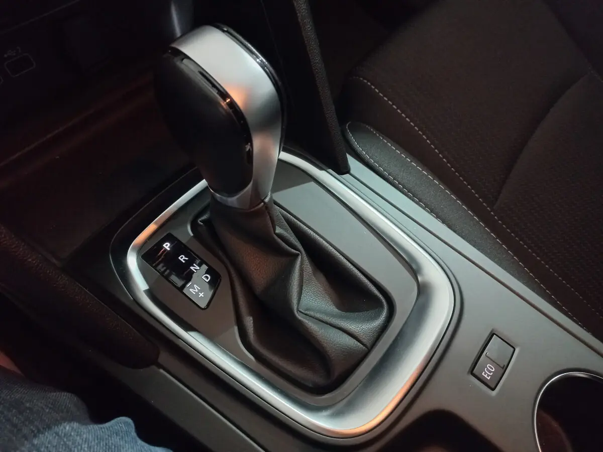 Gros plan sur la commande de boîte automatique noire et argentée dans l'habitacle sombre d'une Renault Megane Business.