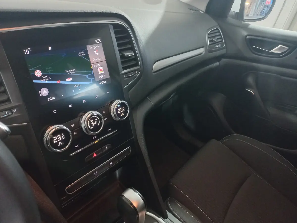 Intérieur avant droit de la Renault Mégane Business blanc, avec écran tactile et commandes climatisation digitales.