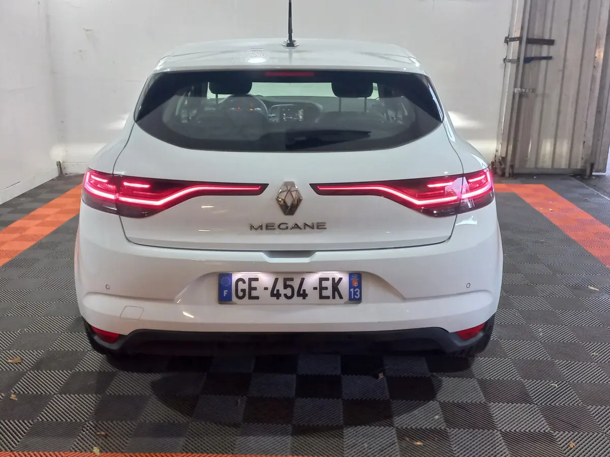 Vue arrière d'une Renault Mégane blanche 2022 avec feux LED allumés et plaque d'immatriculation française visible.