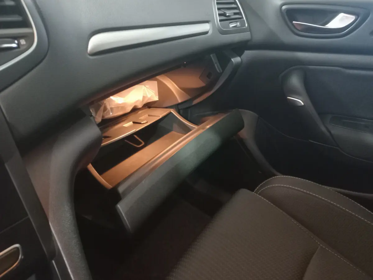 Intérieur noir de la Renault Mégane Business, vue côté passager avec boîte à gants ouverte et siège avant visible.