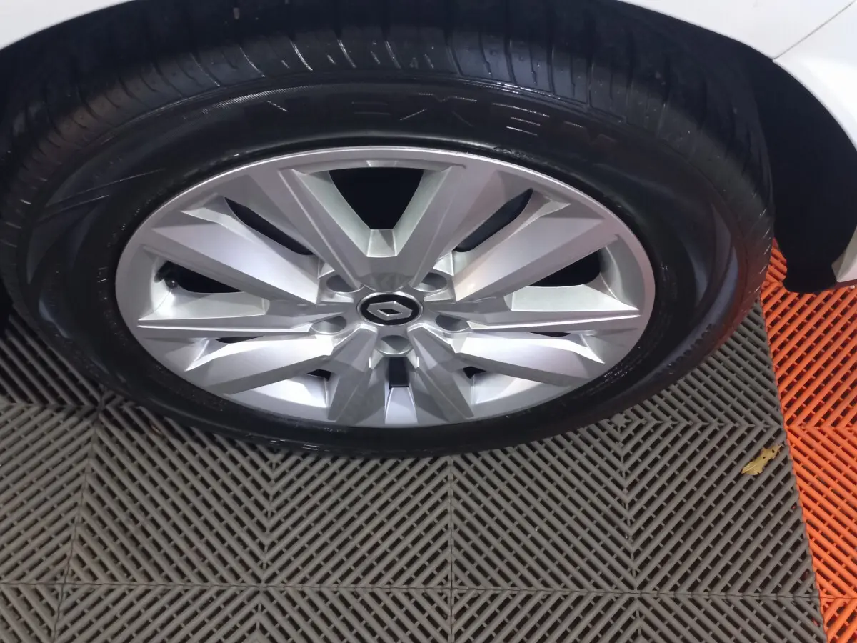 Gros plan sur la roue avant droite d'une Renault Mégane blanche, jante alliage argentée au design moderne.