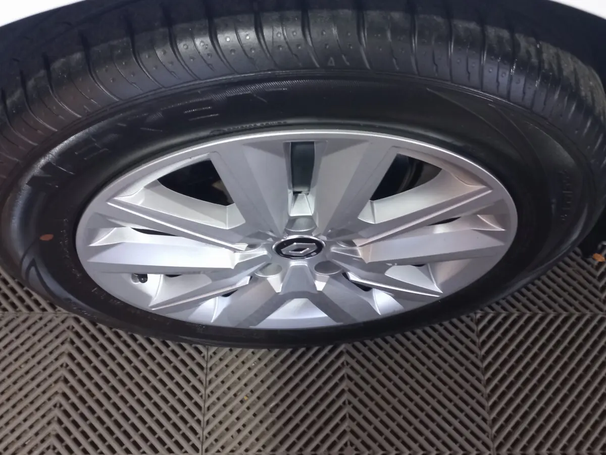 Gros plan sur la jante argentée et le pneu noir d'une Renault Mégane blanche, vue de dessus.