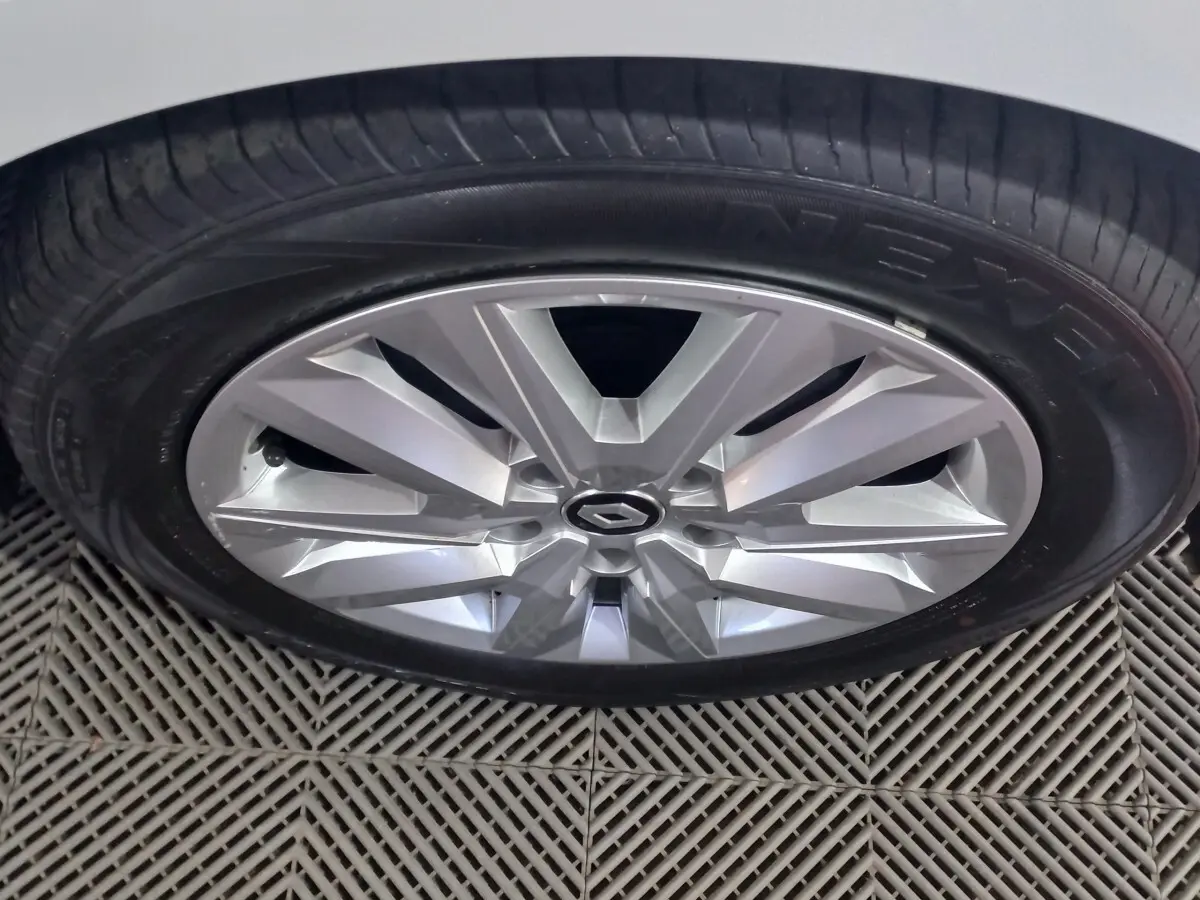 Gros plan sur la jante argentée d'une Renault Mégane blanche, mettant en valeur le logo central et le pneu Nexen.