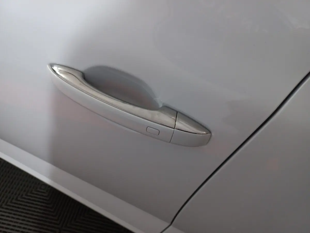 Poignée de porte chromée sur la portière avant gauche d'une Renault Mégane blanche 2022 vue de près.