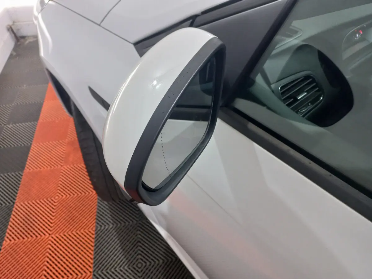 Rétroviseur côté gauche blanc de la Renault Mégane Business Blue dCi 115 EDC 2022, vue rapprochée sur fond de sol noir et orange.