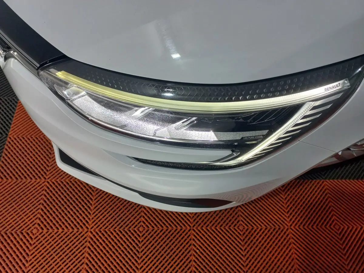 Gros plan sur le phare avant droit blanc d'une Renault Mégane 2022 avec signature lumineuse LED et logo Renault.