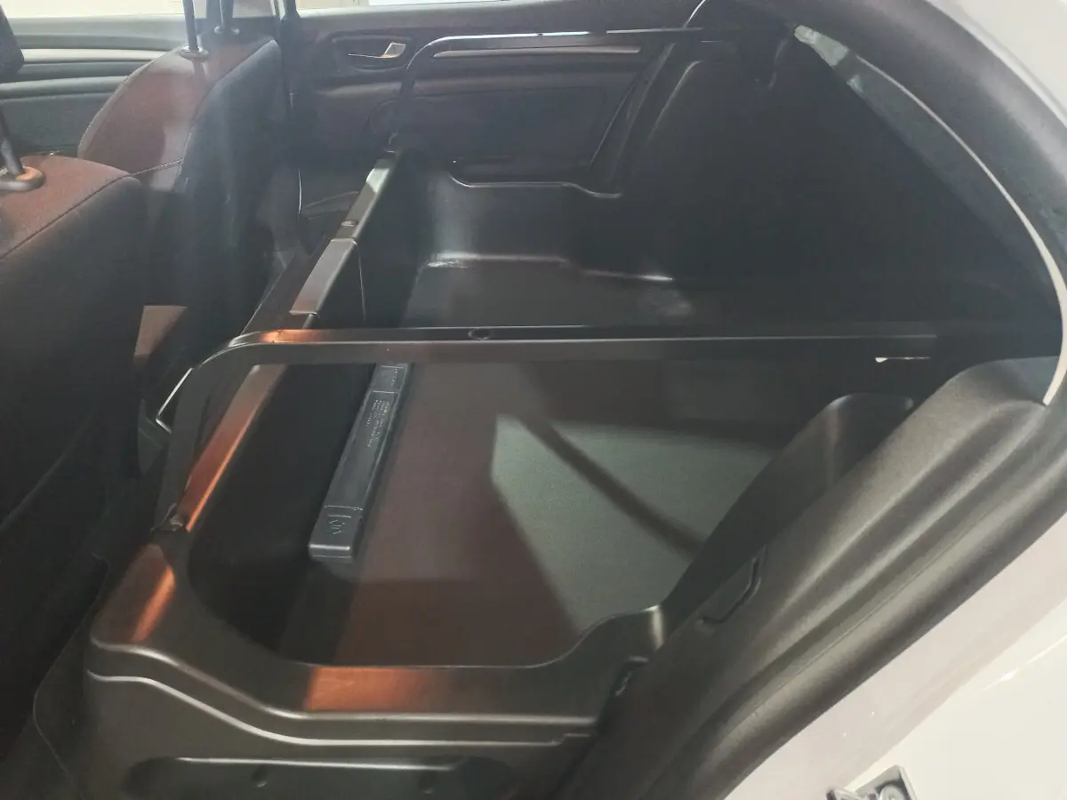 Vue intérieure du coffre ouvert côté droit de la Renault Mégane Business Blue dCi blanc, montrant l'espace de rangement.