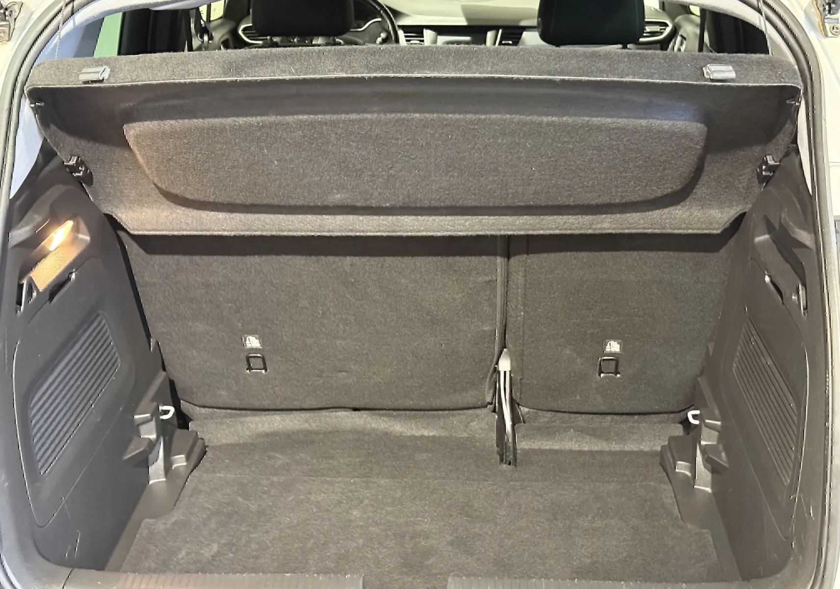 Coffre ouvert de l’Opel Crossland gris 2023, vue arrière montrant l’espace de chargement et la tablette cache-bagages.