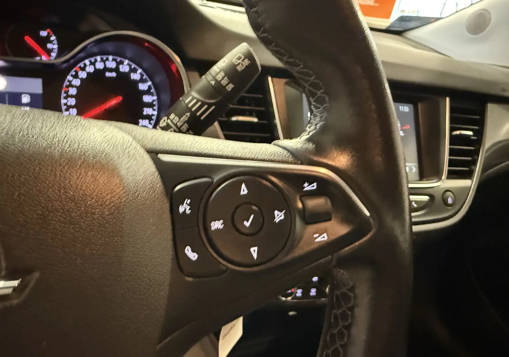 Gros plan sur le volant côté gauche de l’Opel Crossland gris 2023, avec commandes intégrées et tableau de bord en arrière-plan.