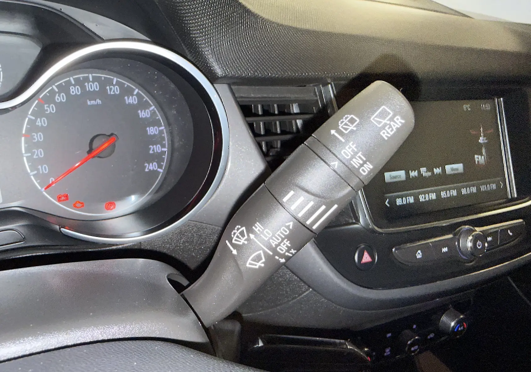 Gros plan sur le commodo d’essuie-glace et le tableau de bord numérique de l’Opel Crossland 2023, intérieur noir.