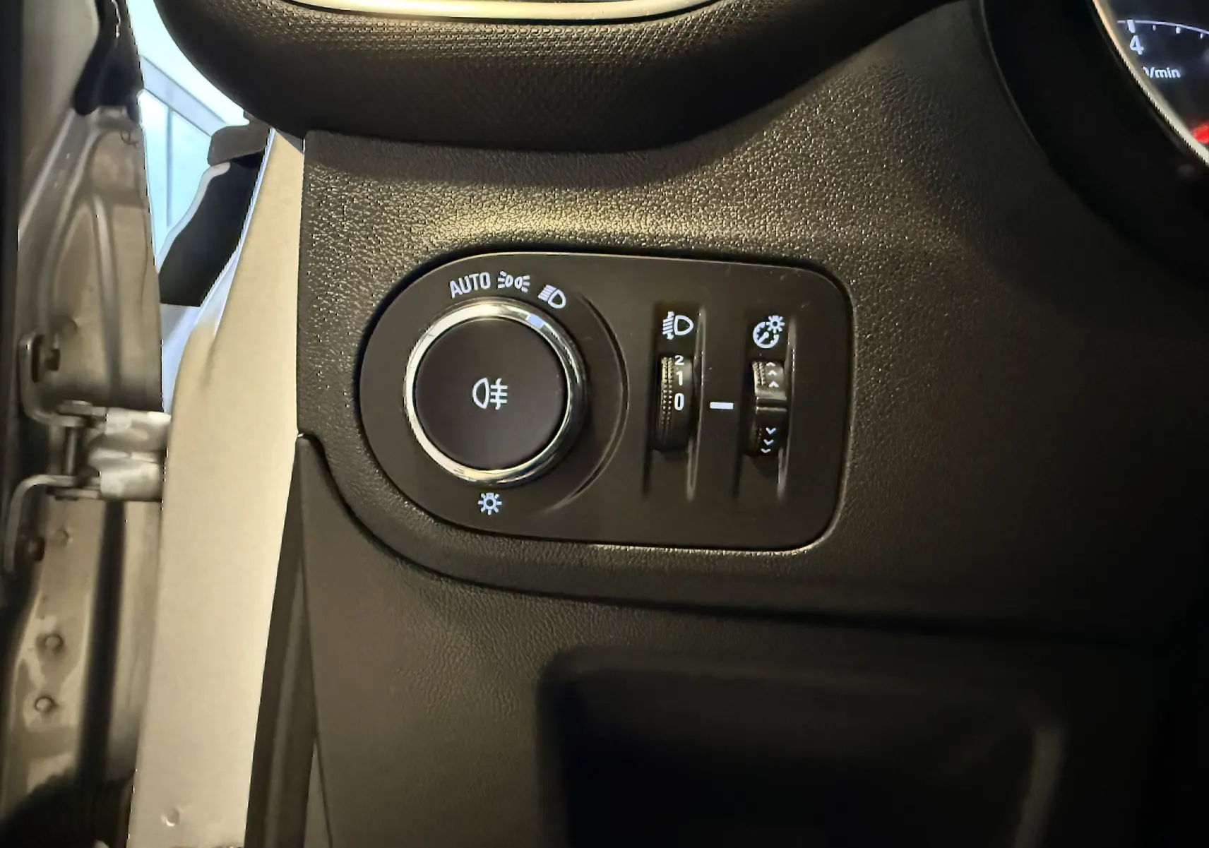 Gros plan sur les commandes d’éclairage intérieures à gauche du volant dans l’Opel Crossland gris 2023, version Essence.