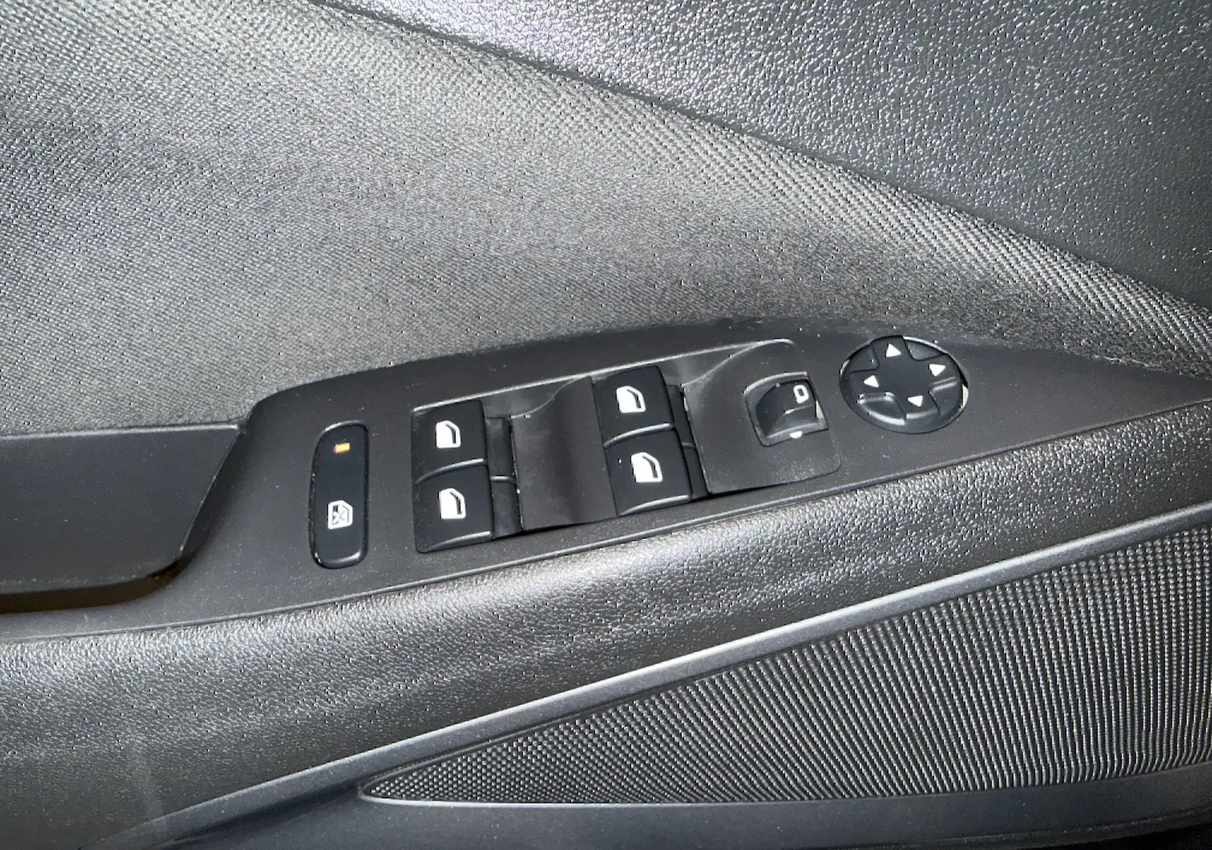 Détail des commandes de lève-vitres et rétroviseurs électriques sur la porte côté gauche d’un Opel Crossland gris 2023.