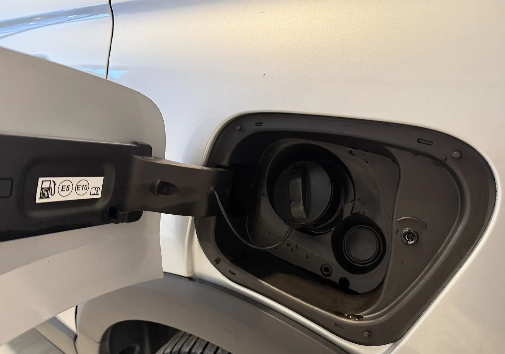 Gros plan sur la trappe à carburant ouverte côté gauche d’un Opel Crossland gris 2023, montrant le bouchon essence.