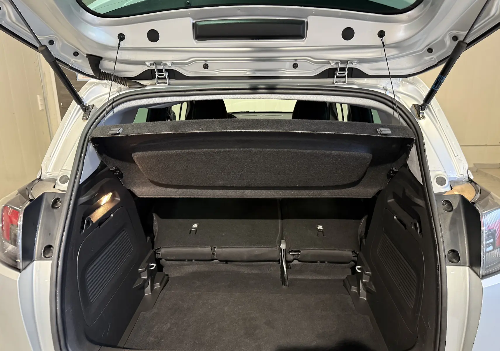 Coffre ouvert vu de l'arrière d'un Opel Crossland gris 2023, montrant l'espace de chargement et la tablette arrière relevée.