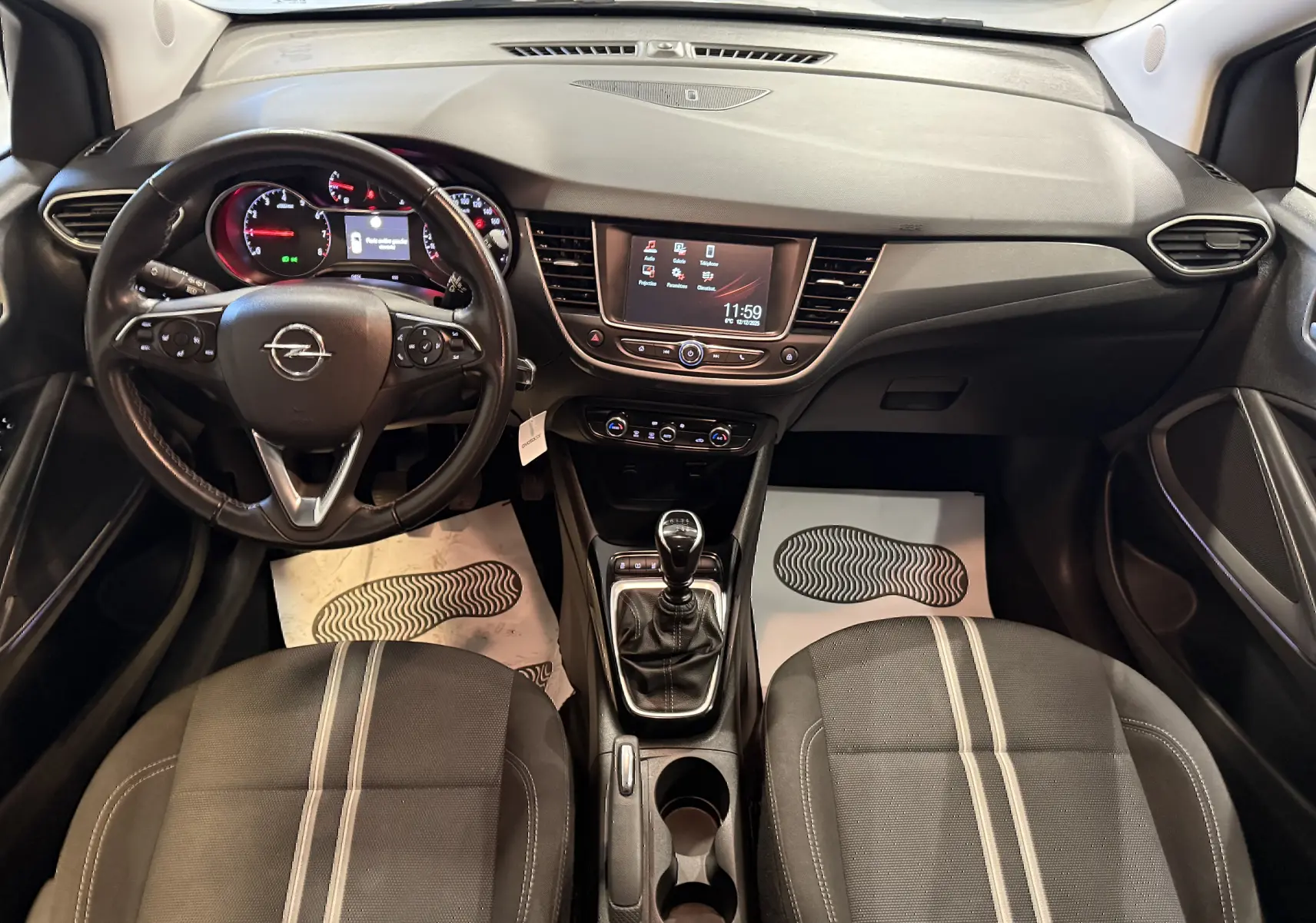 Vue intérieure frontale de l’Opel Crossland 2023, tableau de bord noir avec écran tactile et volant multifonction.