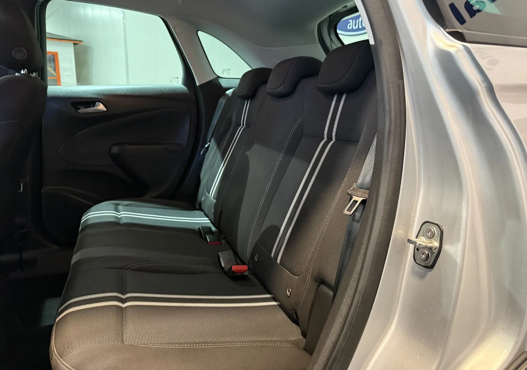 Vue intérieure côté droit sur les sièges arrière noirs avec surpiqûres blanches de l'Opel Crossland gris 2023.