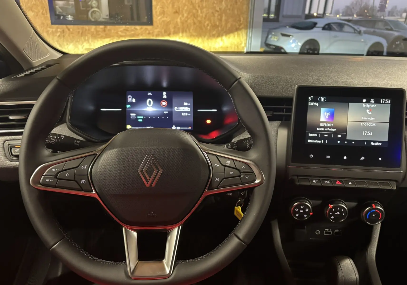 Vue intérieure centrée sur le volant noir de la Renault Clio 2024 avec tableau de bord digital et écran tactile.
