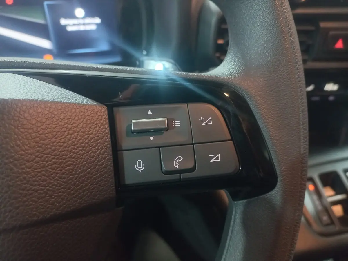 Gros plan sur les commandes multifonctions noires du volant côté gauche du Citroën Berlingo XL 2025, intérieur sombre.