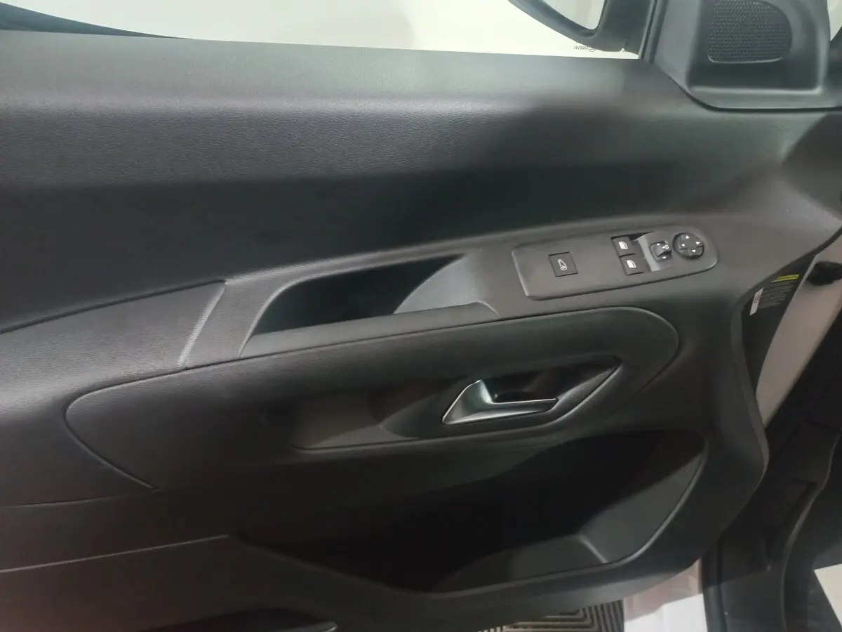 Vue intérieure du panneau de porte côté conducteur du Citroën Berlingo blanc, avec commandes électriques et poignée argentée.