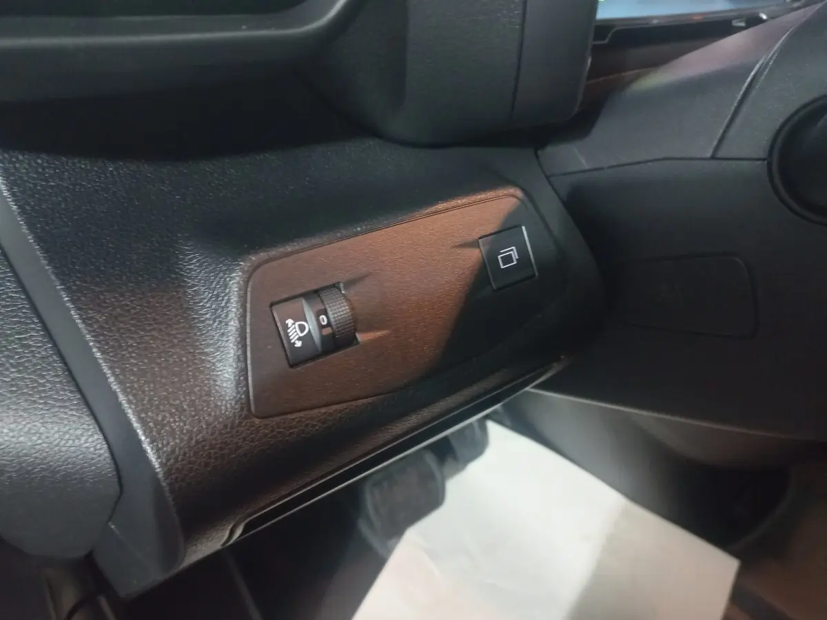 Détail intérieur côté gauche du tableau de bord du Citroën Berlingo XL blanc 2025, avec commandes de réglage des phares.