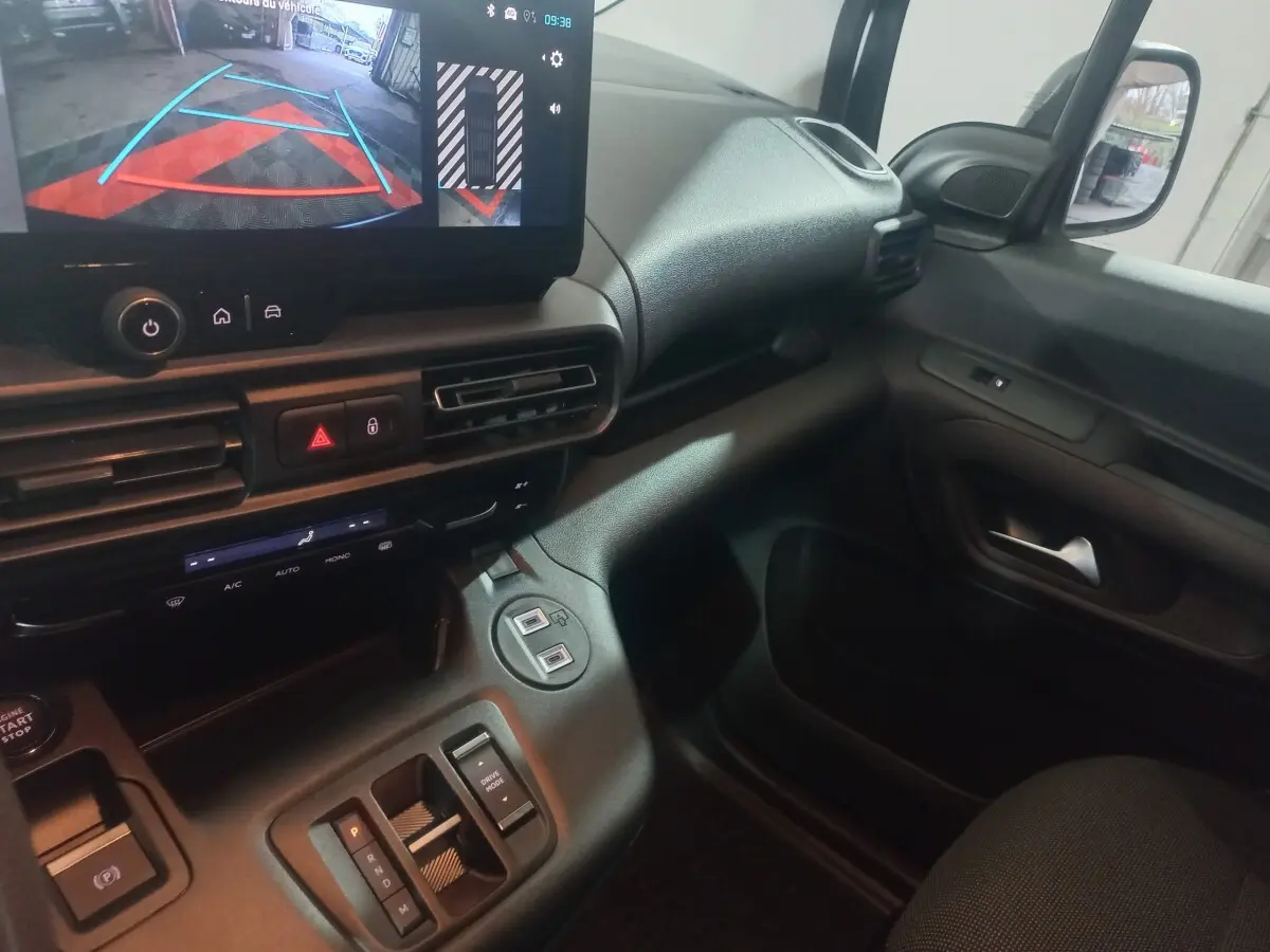 Vue intérieure côté passager du tableau de bord et console centrale du Citroën Berlingo blanc, avec écran multimédia affichant la caméra de recul.