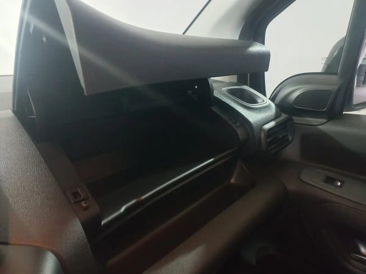 Vue intérieure côté passager du coffre à gants ouvert du Citroën Berlingo XL blanc, avec aérateur et rétroviseur visible.