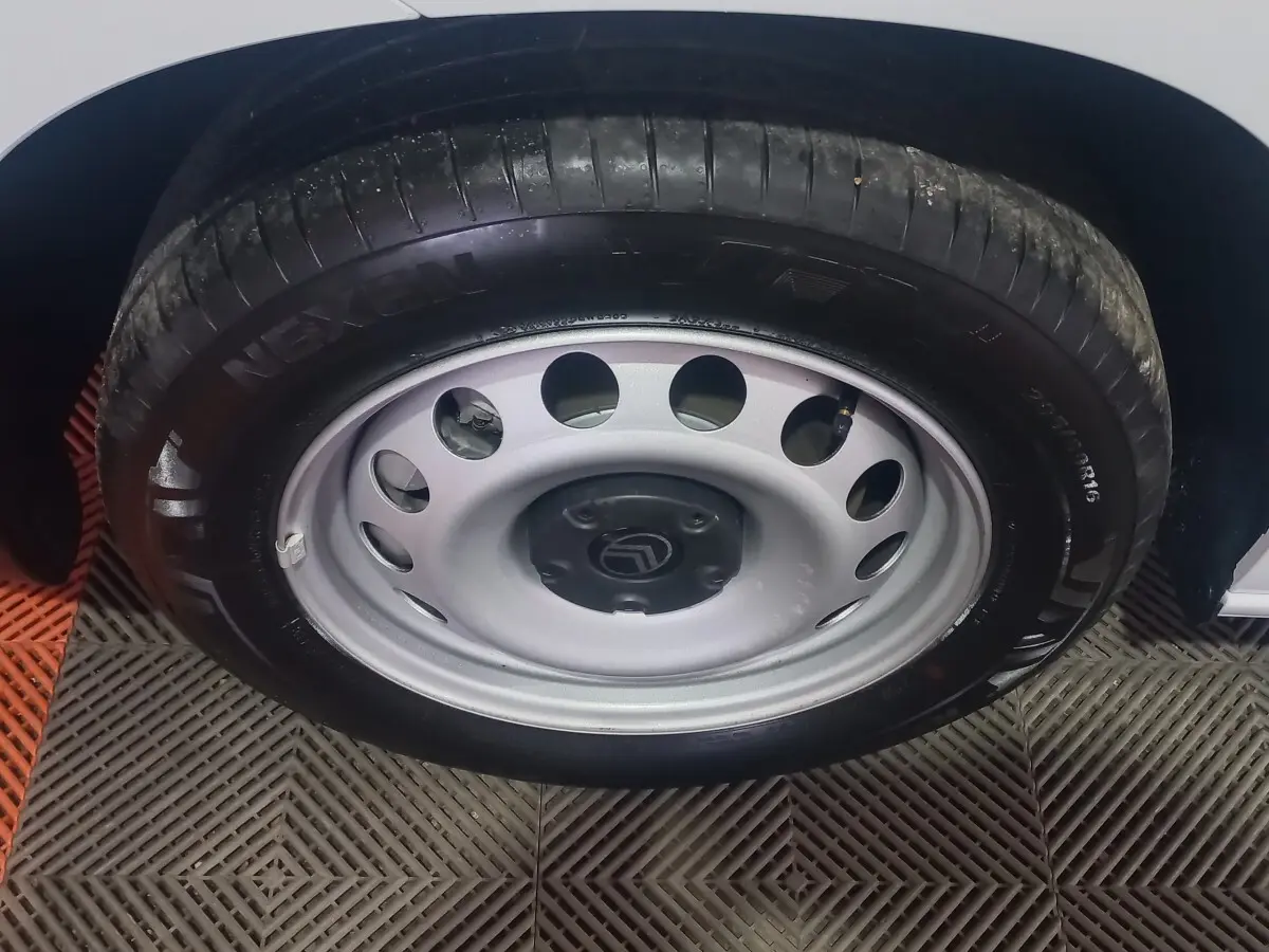 Gros plan sur la roue avant droite du Citroën Berlingo blanc, jante acier avec logo Citroën au centre.