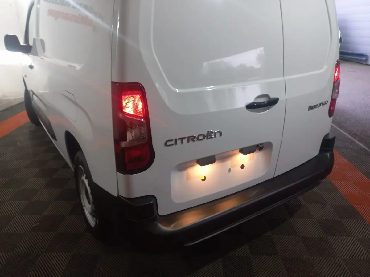 Vue 3/4 arrière droite du Citroën Berlingo blanc 2025 avec feux arrière allumés et porte arrière fermée.