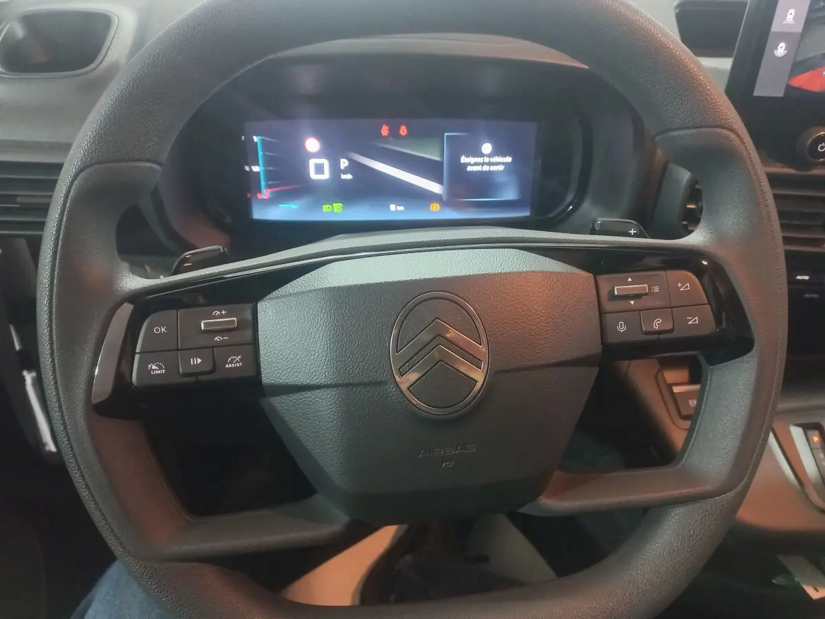 Vue rapprochée du volant noir du Citroën Berlingo XL 2025 avec commandes intégrées et tableau de bord numérique.