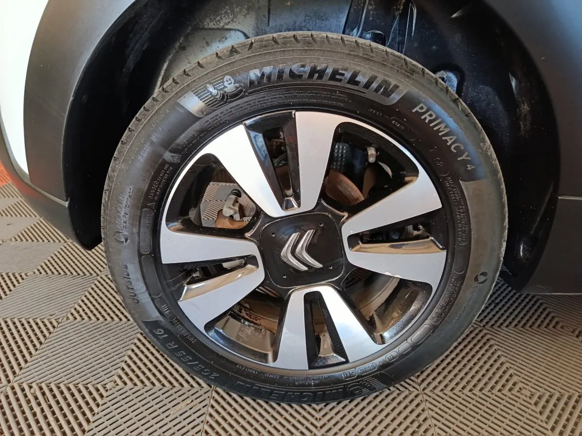 Gros plan sur la roue avant gauche d'une Citroën C3 blanche, mettant en valeur la jante alliage bicolore et le pneu Michelin.