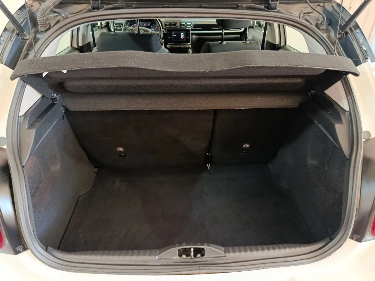 Coffre ouvert d'une Citroën C3 blanche, vue arrière montrant l'espace de chargement et l'intérieur sombre.