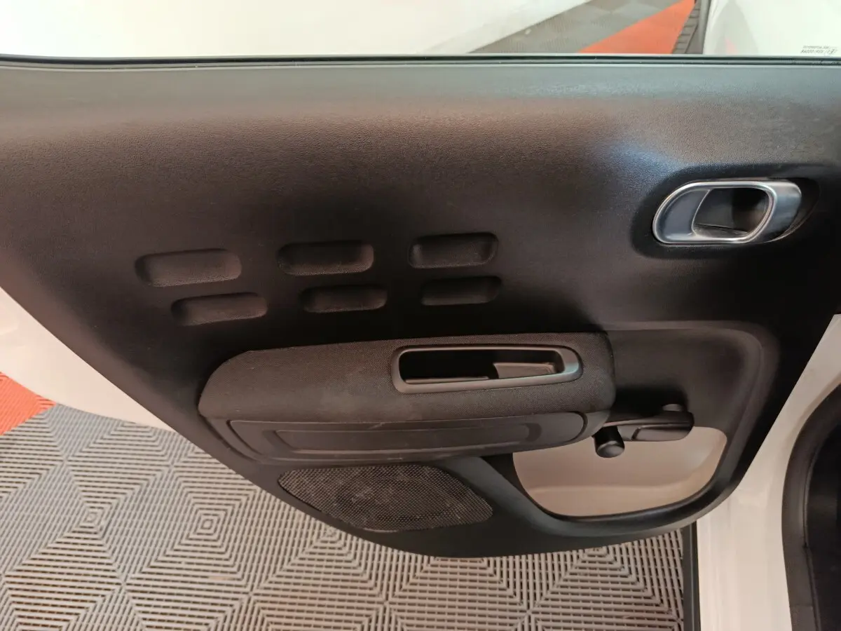 Vue rapprochée de la porte avant gauche noire et blanche de la Citroën C3 avec poignée et commande de vitre manuelle.
