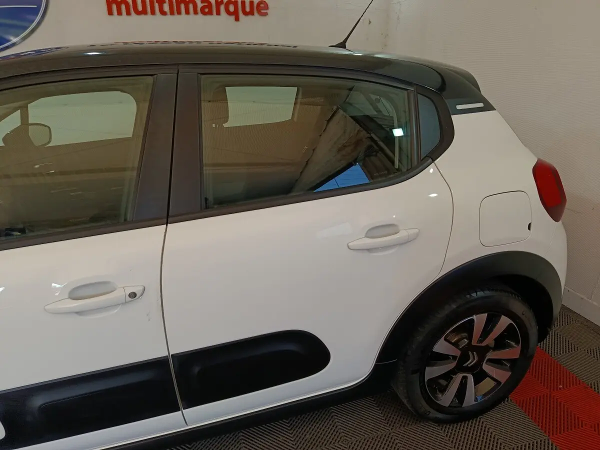 Vue côté droit arrière d'une Citroën C3 blanche avec protections latérales noires et jantes stylisées.