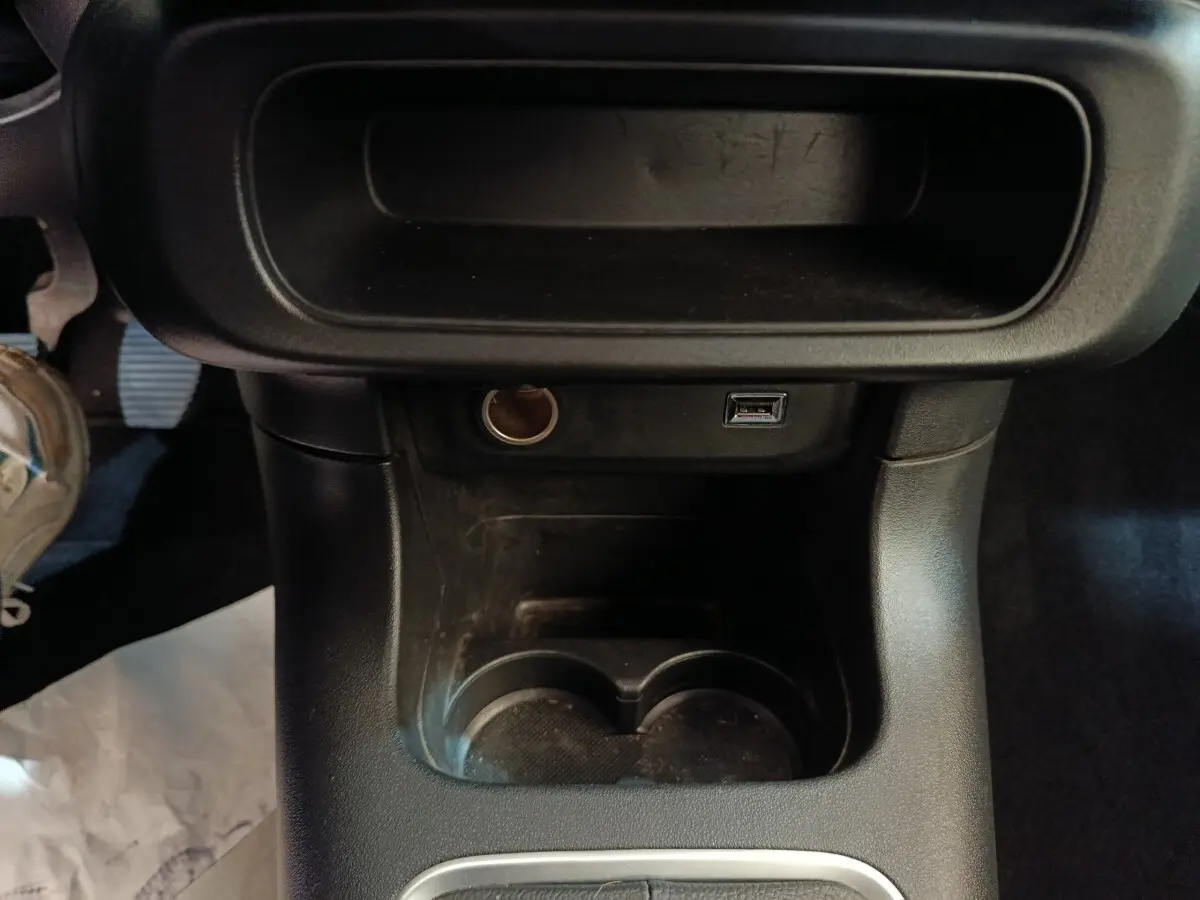 Vue rapprochée de la console centrale noire avec prises USB et allume-cigare dans une Citroën C3 blanche 2021.