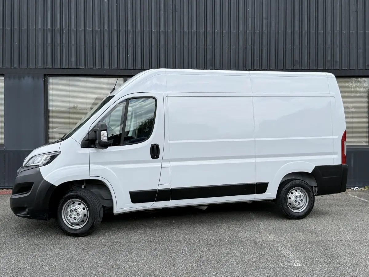 Vue de profil côté gauche d’un Peugeot Boxer Fourgon blanc avec protections noires et jantes acier.