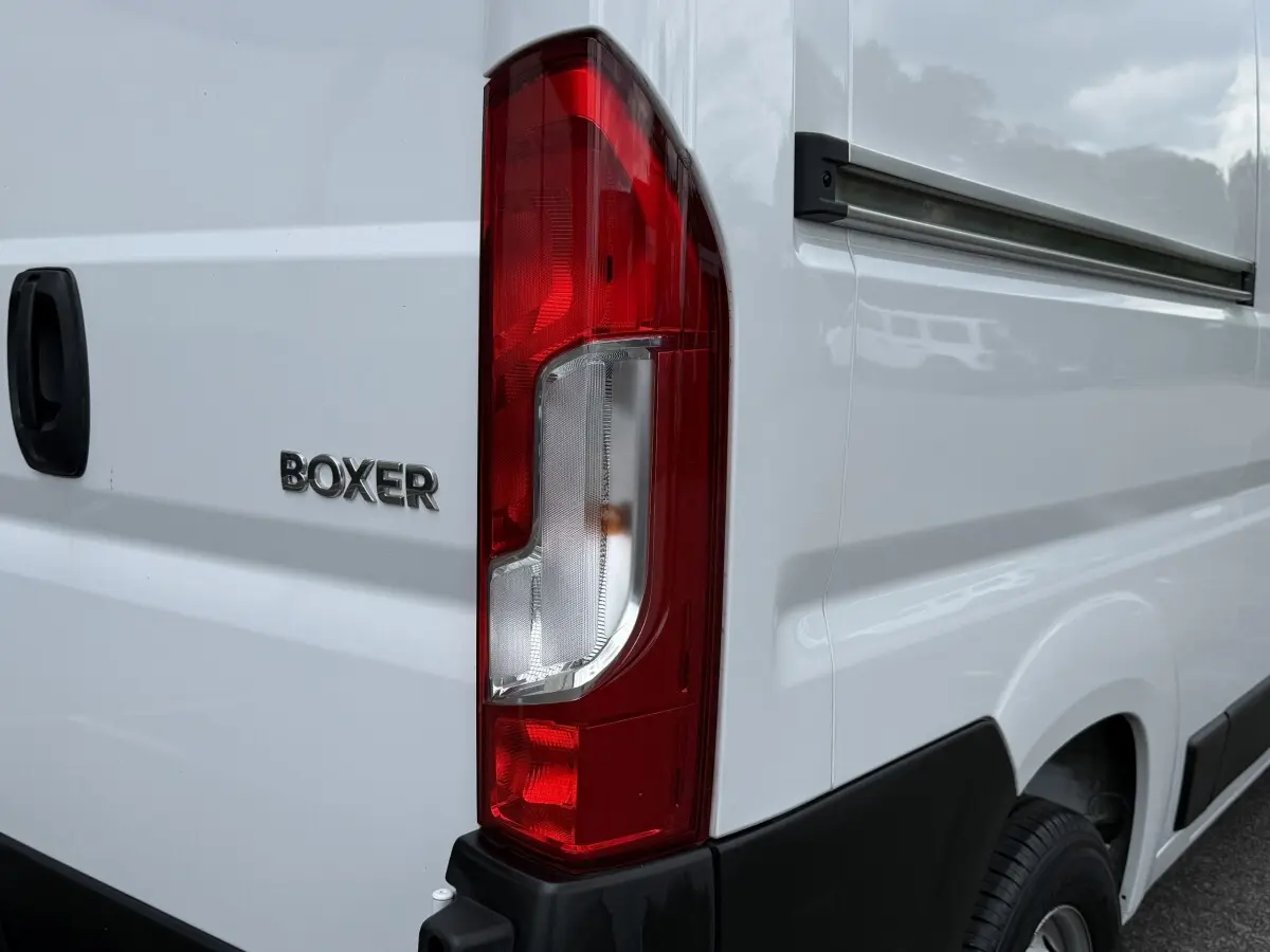 Gros plan sur l'arrière droit blanc du Peugeot Boxer Fourgon avec feu arrière rouge et logo BOXER visible.