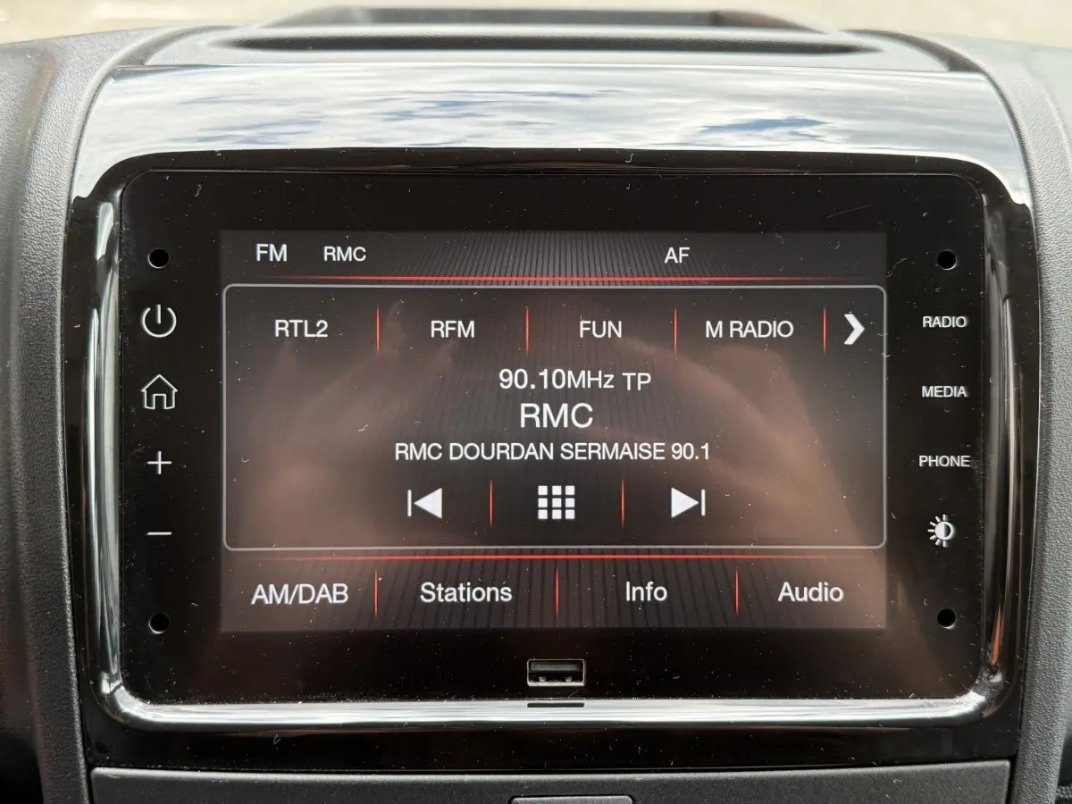 Écran tactile central du tableau de bord du Peugeot Boxer Fourgon blanc, affichant la radio FM RMC.