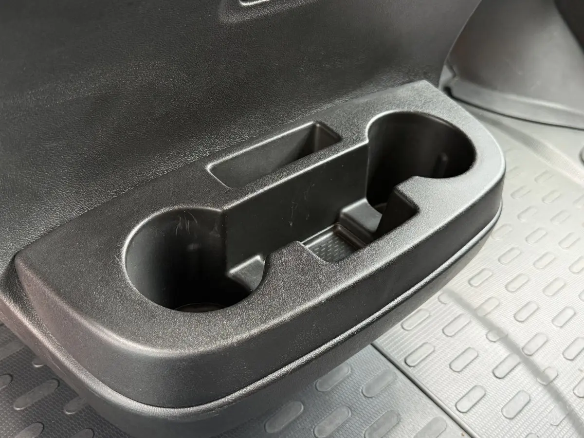 Gros plan sur le porte-gobelets noir côté passager du Peugeot Boxer Fourgon blanc, avec tapis caoutchouc gris en arrière-plan.