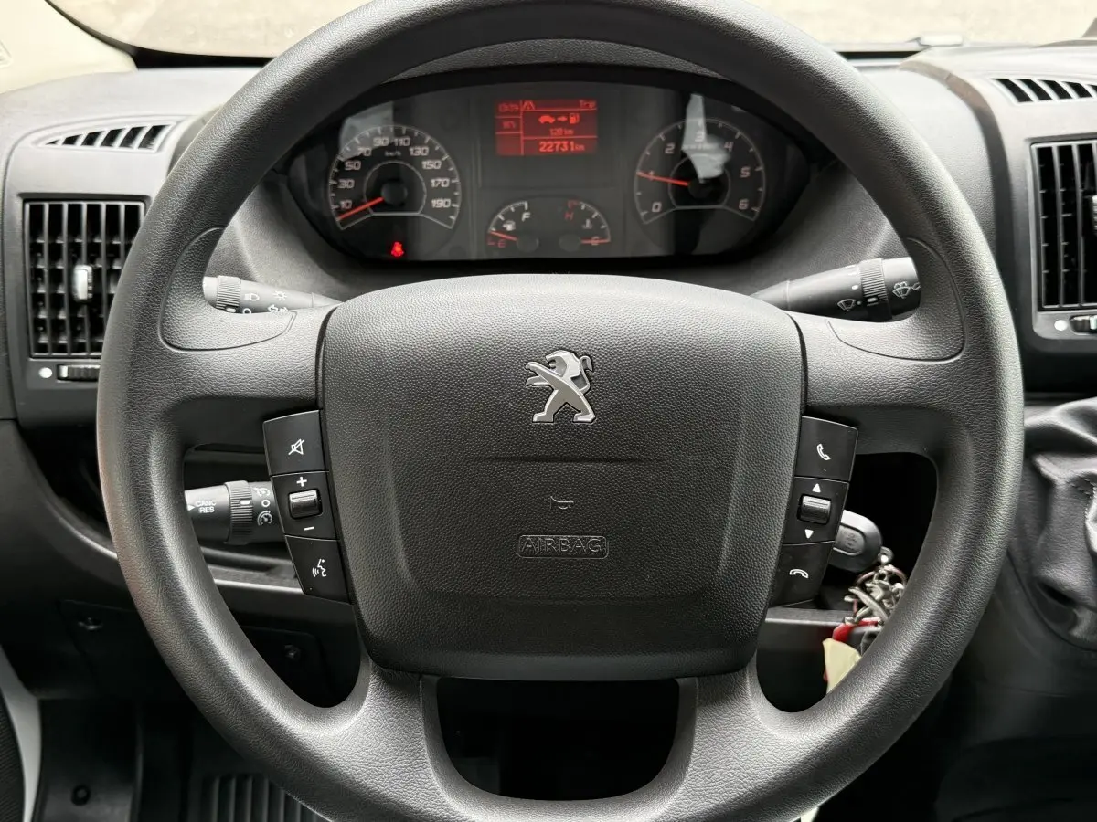Vue rapprochée du volant noir multifonctions et du tableau de bord numérique du Peugeot Boxer Fourgon 2023.