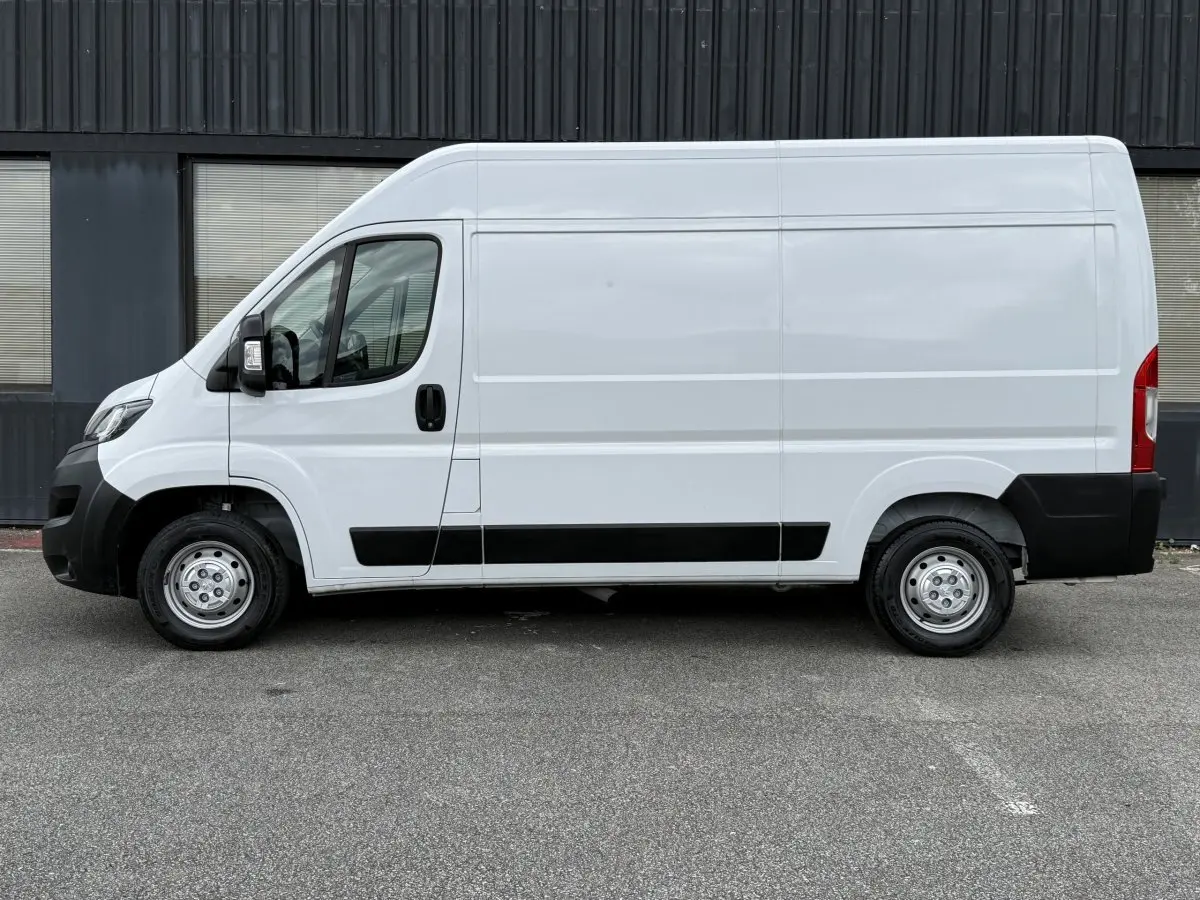 Vue de profil côté gauche d’un utilitaire Peugeot Boxer Fourgon blanc avec protections noires et jantes acier.