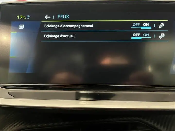 Écran tactile du tableau de bord de la Peugeot e-208 GT 2022 affichant les réglages des feux en mode clair.