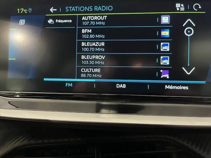 Écran tactile central affichant les stations radio FM dans l'habitacle de la Peugeot 208 E-208 GT gris Artense.