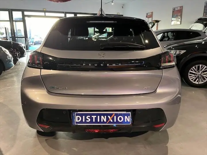 Vue arrière d'une Peugeot 208 E-208 GT électrique en gris Artense, avec logo et feux arrière LED distinctifs.