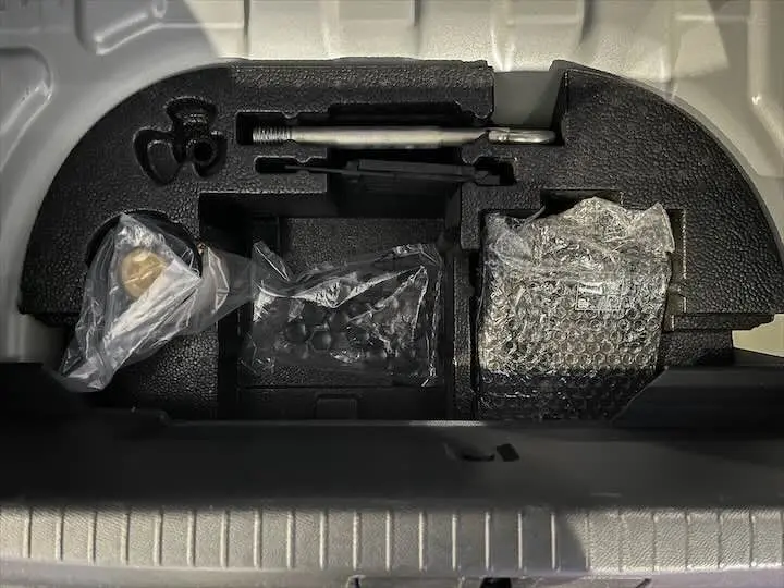 Rangement sous le coffre de la Peugeot 208 E-208 GT gris Artense avec outils et accessoires emballés.