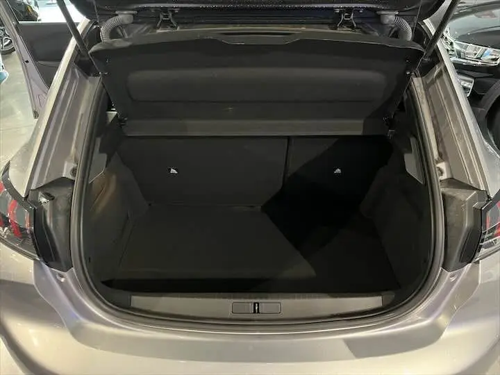 Coffre ouvert vu de l'arrière d'une Peugeot 208 E-208 GT gris Artense, montrant un espace de chargement vide.